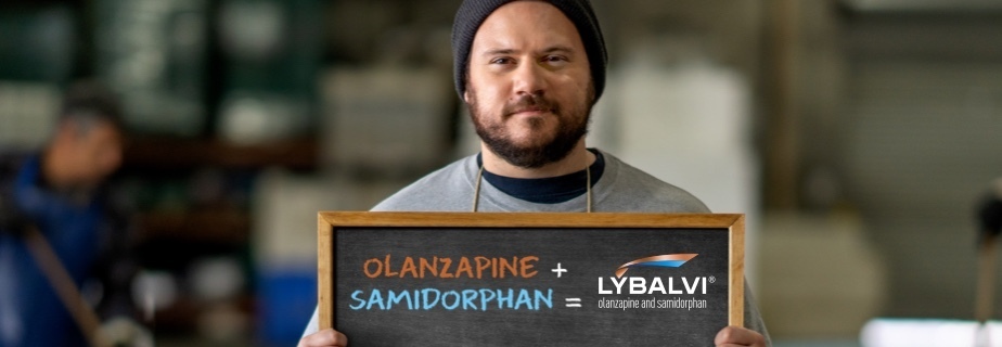 Review the efficacy and safety of LYBALVI® (olanzapine and samidorphan) Man standing in a warehouse, holding a sign that shows the components of LYBALVI® (olanzapine and samidorphan)